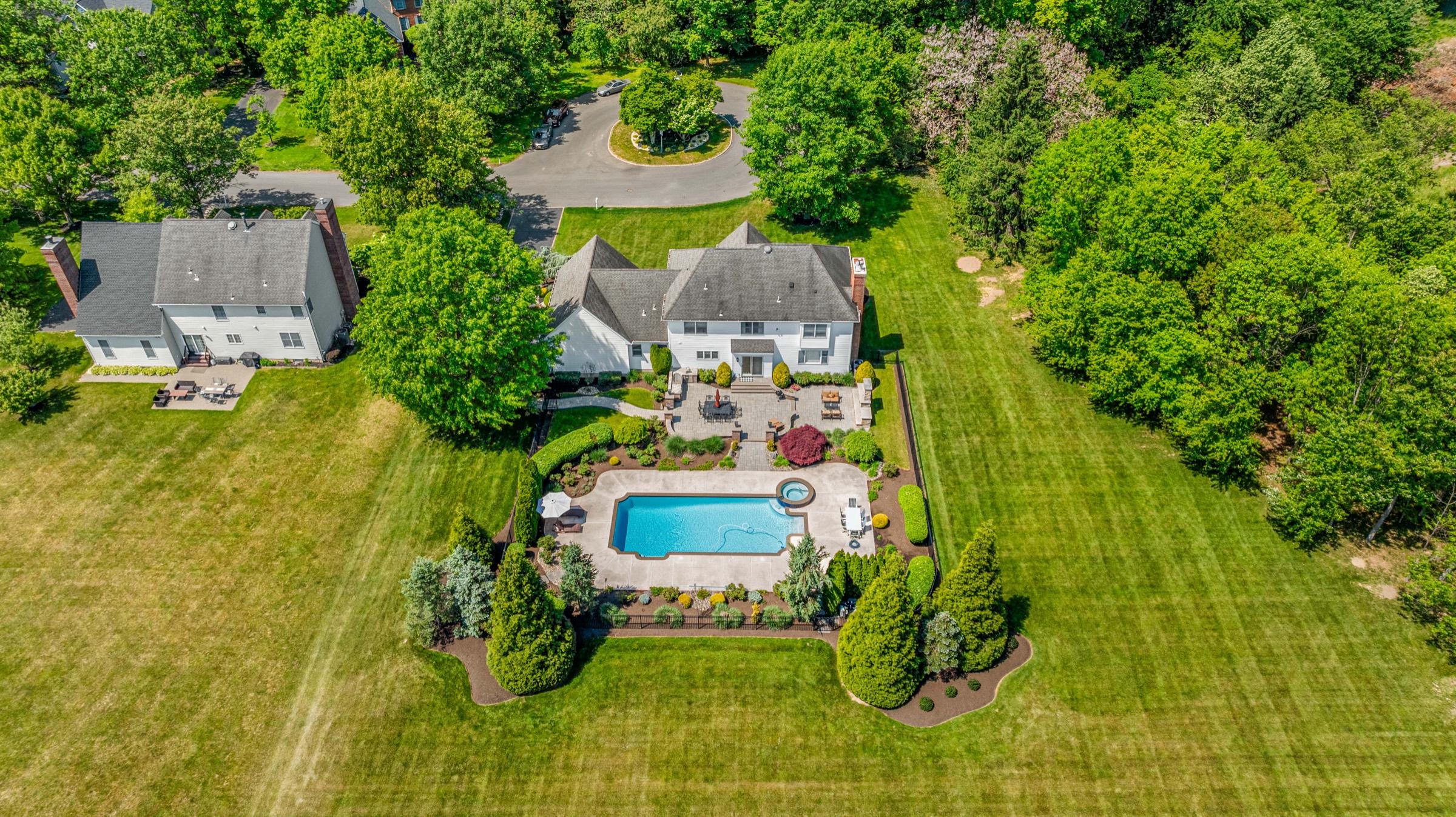 Aerial drone view of an estate backyard with a pool and patio