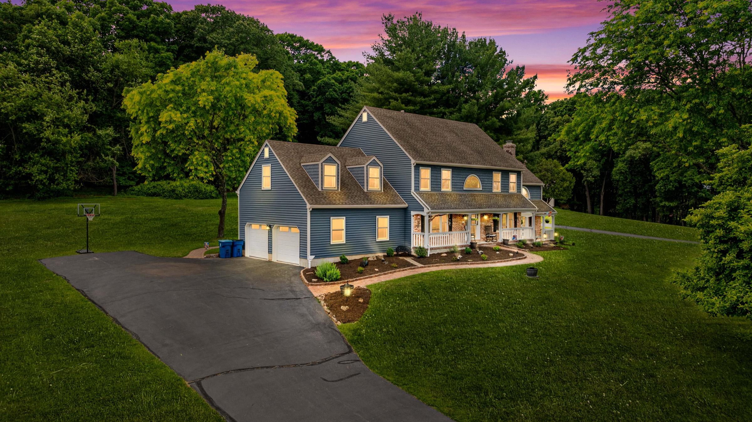 Elevated twilight view of a blue colonial home under a pink and purple sky