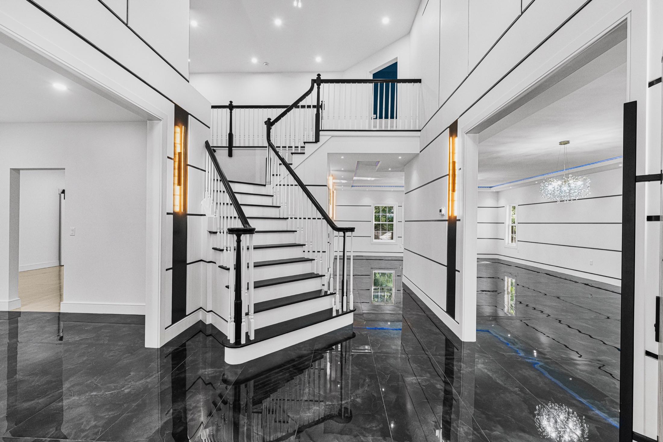 Two-story foyer with polished black marble floors and a dramatic black & white staircase, new-construction NJ home