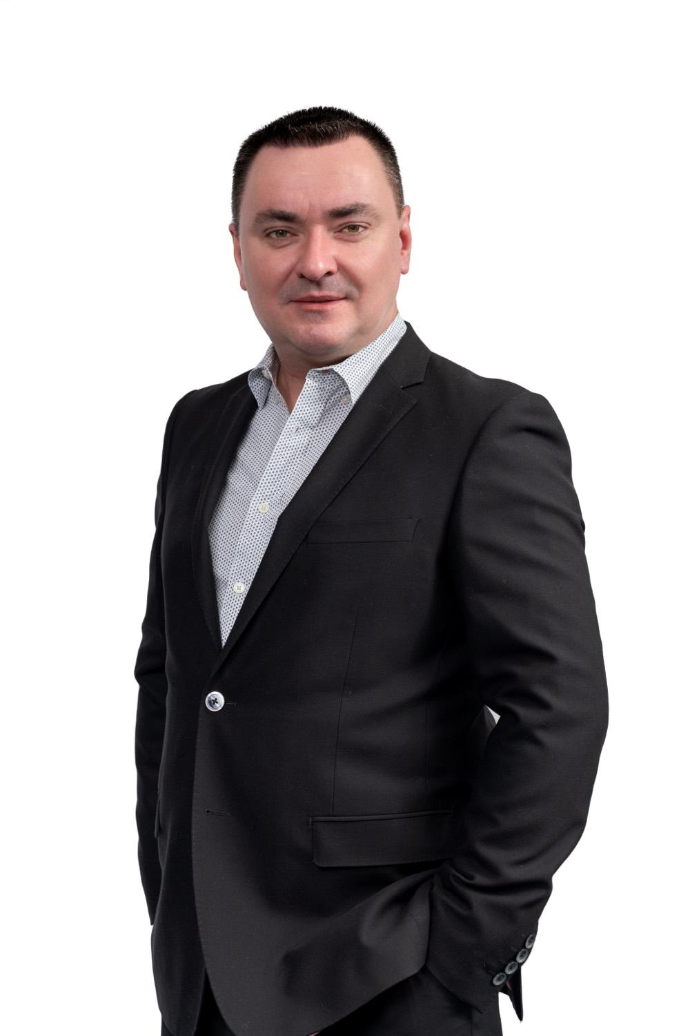 Corporate headshot of a man in a dark suit on a white background