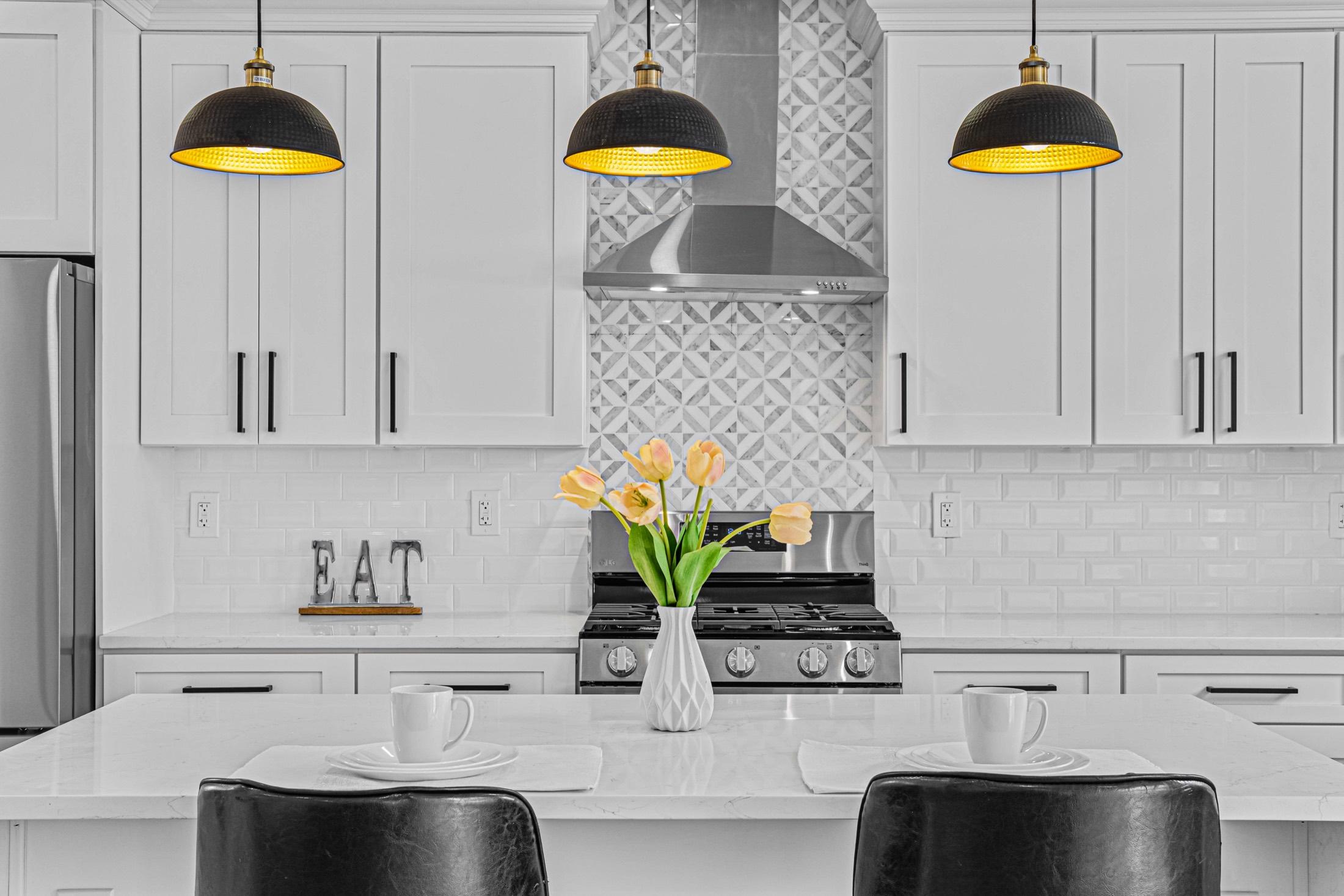 Modern white kitchen detail with black pendant lights and fresh tulips
