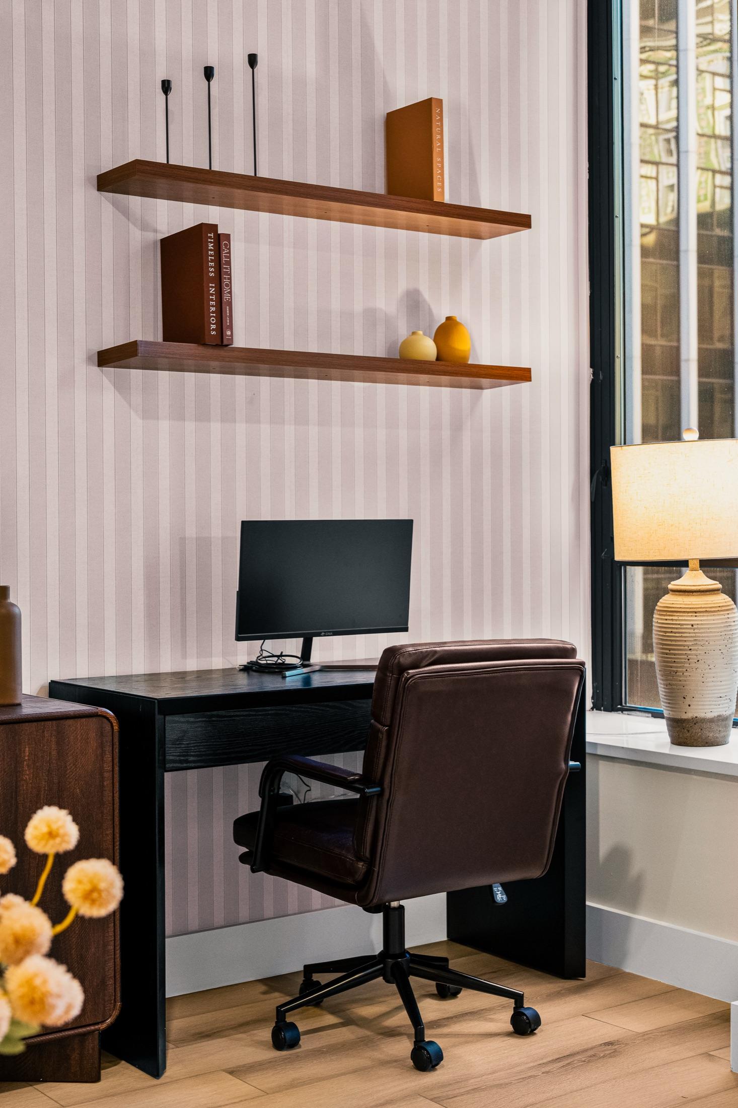 Dedicated workspace with desk, leather chair, and floating shelves in a Manhattan short-term rental