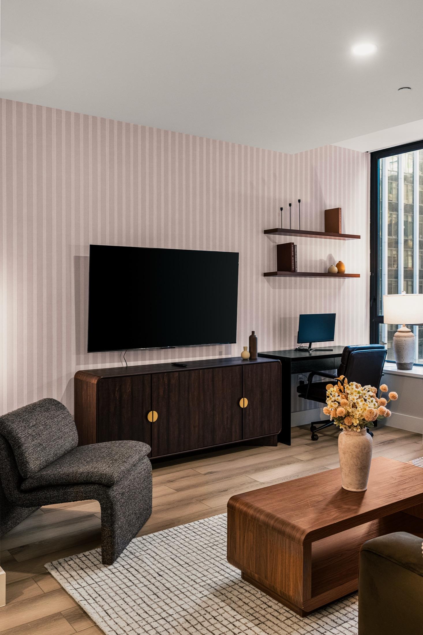 Living area with TV wall, walnut media console, and work nook, Financial District NYC short-term rental