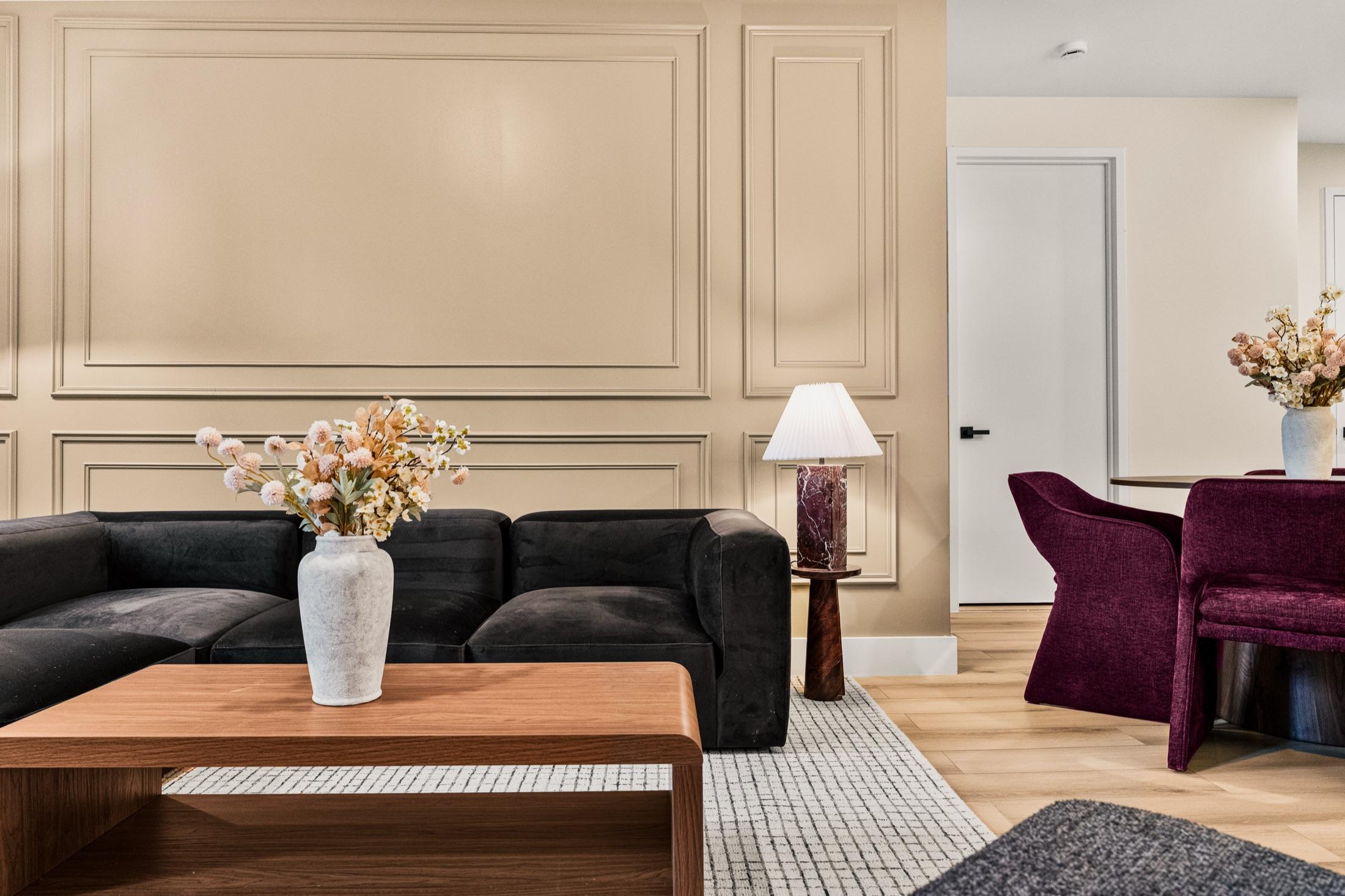 Living room with black velvet sectional, panel molding, and velvet dining chairs, New York City short-term rental