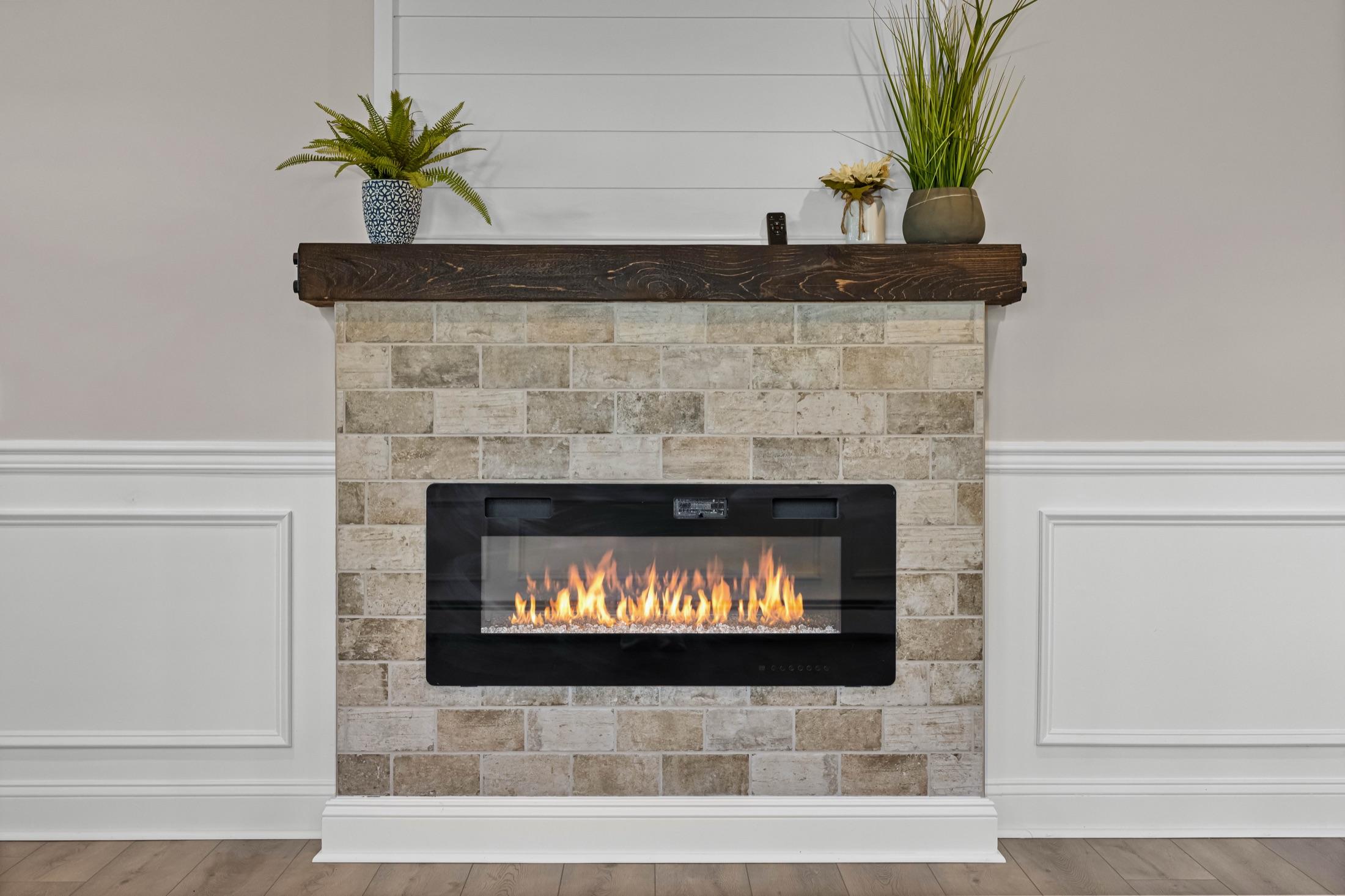 Electric fireplace detail with brick surround, rustic wood mantel & shiplap accent wall