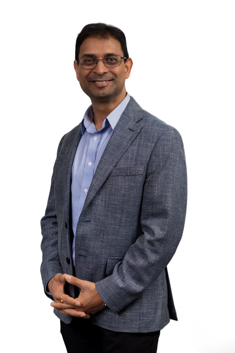 Professional corporate headshot of a man, seated