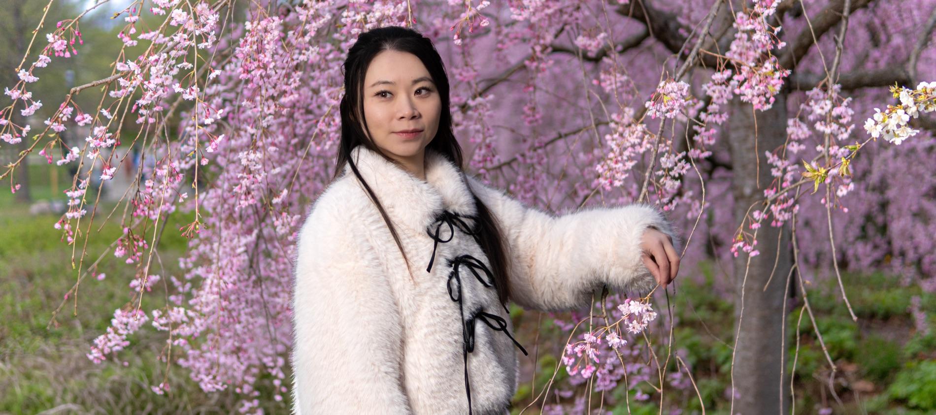 Spring portrait of a woman beneath blossoming cherry trees